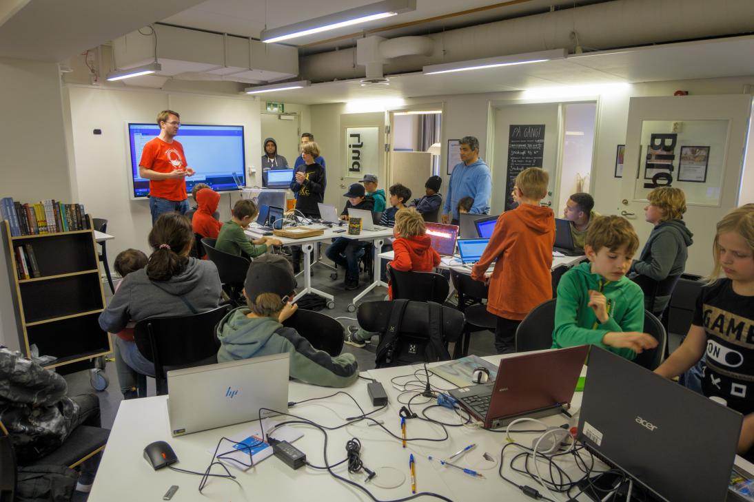 Våra elever (i röda T-shirts) hjälper till på Programmeringsdag på Uppsala Stadsbibliotek